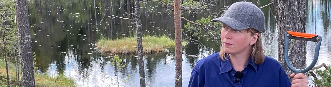 Kvinna med barkspade i skogsmiljö